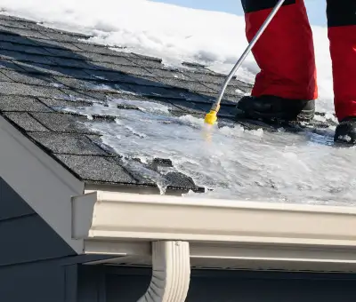 Ice dam removal technician using a steam wand to melt thick ice buildup on a residential roof in Chicago, IL